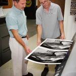 Two men looking at newly printed photos on canvas